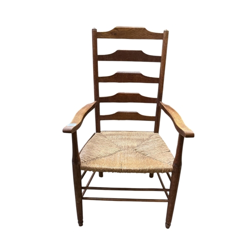 1085 - A pair of Arts & Crafts oak ladderback rush seat elbow chairs, width 62cm, depth 47cm, height 108cm... 