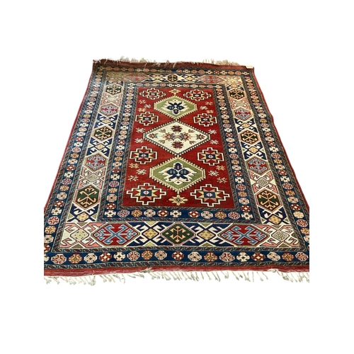 126 - A Caucasian Kazak style rug, woven with geometric designs in iron red and blue, 200cm x 146cm