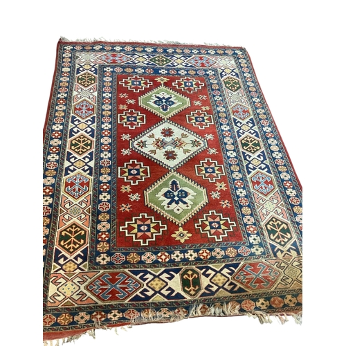 126 - A Caucasian Kazak style rug, woven with geometric designs in iron red and blue, 200cm x 146cm