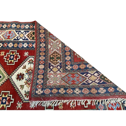 126 - A Caucasian Kazak style rug, woven with geometric designs in iron red and blue, 200cm x 146cm