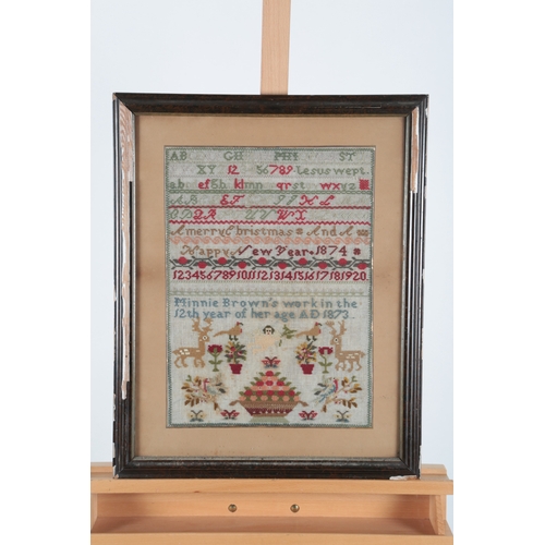 84 - A 19th century wool worked sampler by Minnie Brown, aged twelve years, dated 1873. A colourful polyc... 
