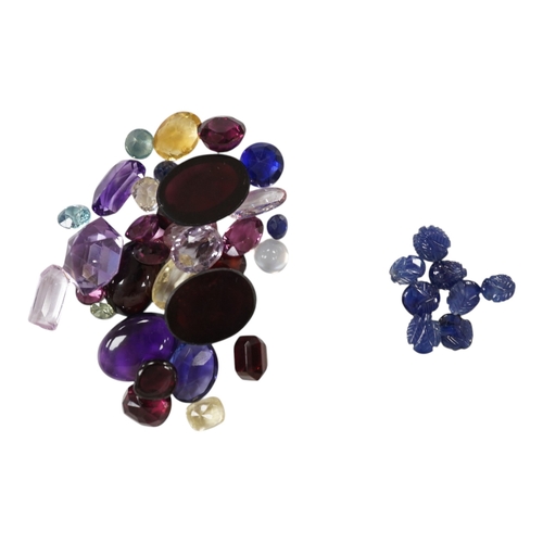 3131 - A collection of loose stones including carved sapphires and variously shaped moonstone, garnets and ... 