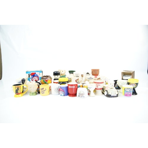 104 - A Collection of Approximately 35 Novelty and Advertising Egg Cups Featuring Various British Food and... 