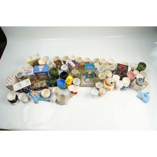 67 - A Collection of Novelty and Character-Themed Ceramic Egg CupsA varied collection of ceramic egg cu... 