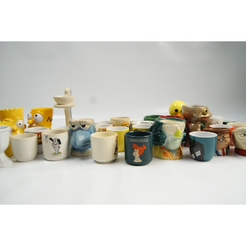 69 - A Collection of Novelty and Character Ceramic Egg CupsA varied collection of novelty egg cups cons... 