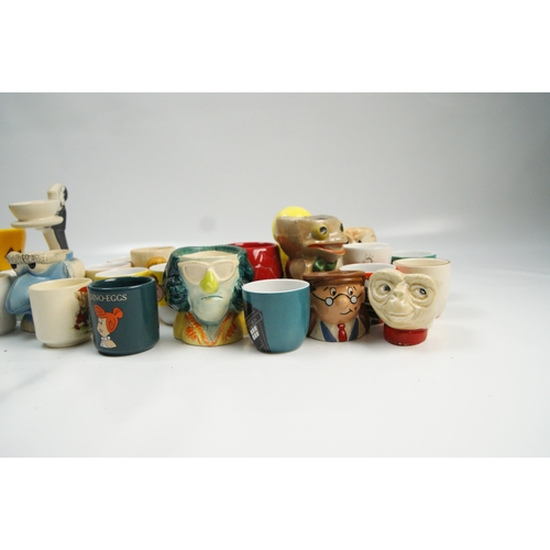 69 - A Collection of Novelty and Character Ceramic Egg CupsA varied collection of novelty egg cups cons... 