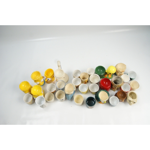 69 - A Collection of Novelty and Character Ceramic Egg CupsA varied collection of novelty egg cups cons... 
