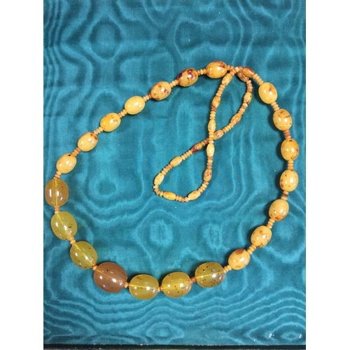 20 - A long string of amber coloured beads,
set with associated amber coloured beads to front -