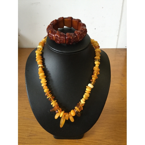 21 - An egg yolk amber necklace,
together with a bracelet composed of Buddha heads -