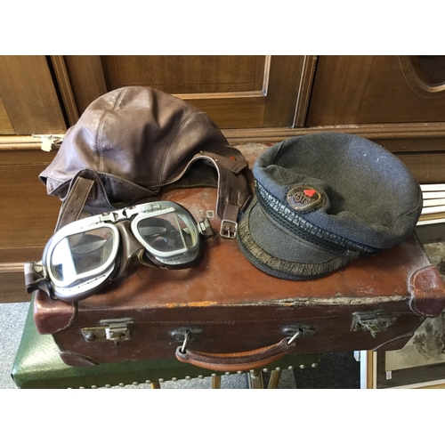 419 - A vintage case,
containing leather driving hat and goggles and a cap -