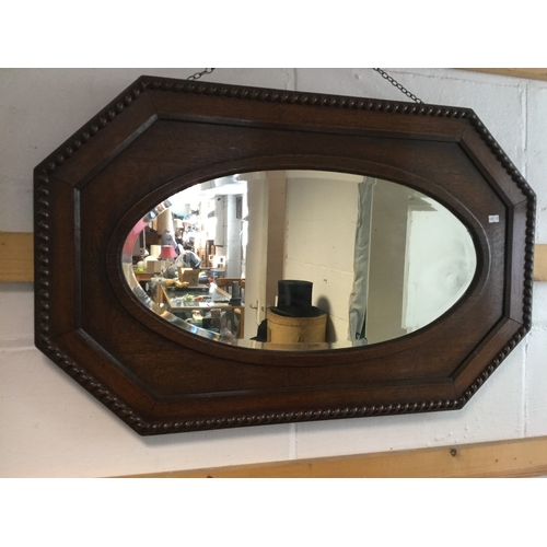 384 - An early 20th century oak framed wall mirror,
with bevelled oval plate in octagonal frame -