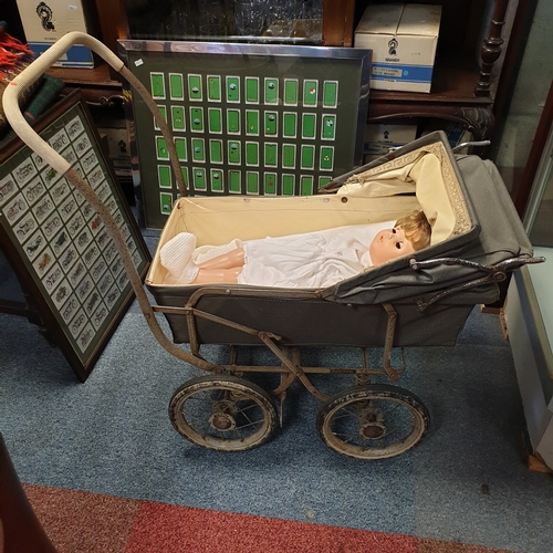194 - A vintage dolls pram, 
coach sprung, together with a doll -
