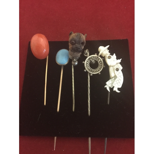 17 - A group of five antique stick pins, 
to include examples set with articulated mother-of-pearl figure... 