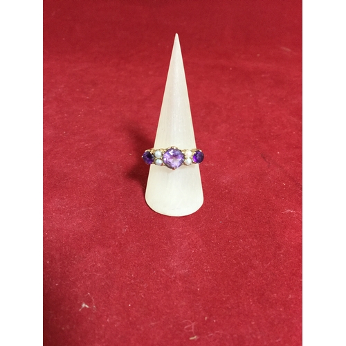 44 - A 9ct gold dress ring, 
set with three graduated amethysts spaced by pairs of pearls -