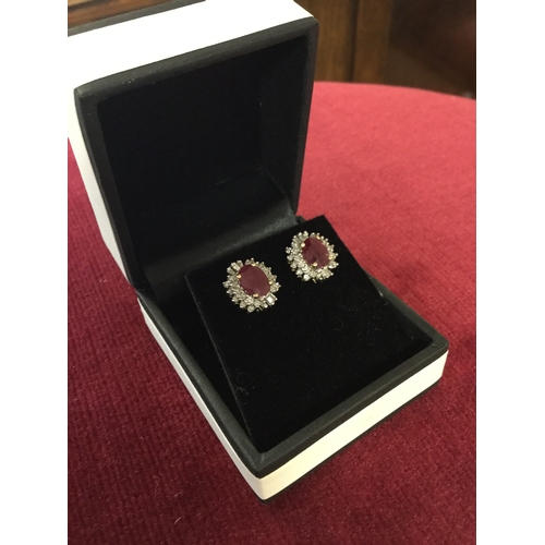 37 - A pair of ruby and diamond earrings, 
each with oval ruby in a diamond border, to 14ct gold -