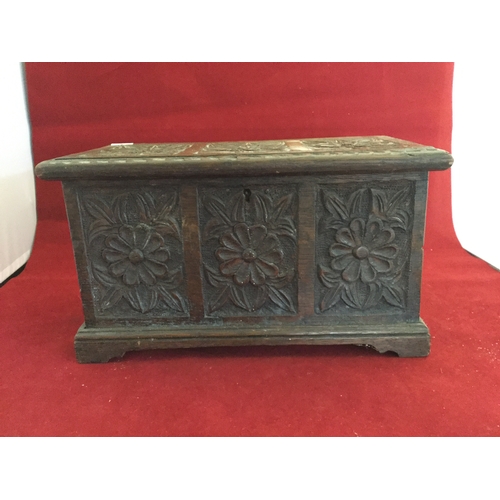 83 - A carved oak box, decorated to each side with flowerheads and raised on short legs -