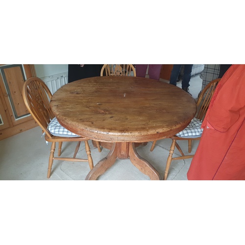 326 - A pine dining table, with circular top on central column and four wheelback chairs -