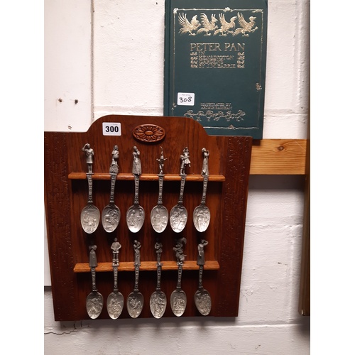 300 - A set of twelve Franklin Mint spoons, each depicting a fairy tale, on rack, and a Peter Pan volume -