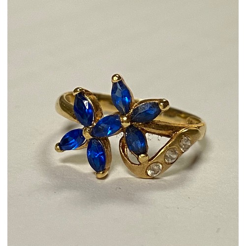 14 - A gem set dress ring, stamped 750+ with continental marks, set with a blue and white stone flowerhea... 