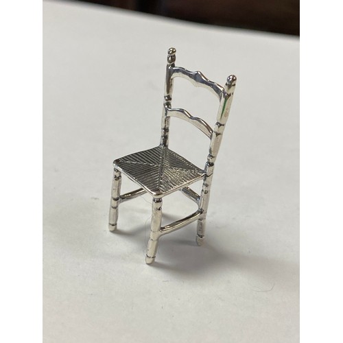 53 - A silver miniature model chair, stamped 925 -