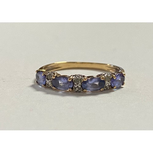 31 - A tanzanite and diamond set band ring, set with four oval tanzanites with pairs of diamond spacers, ... 