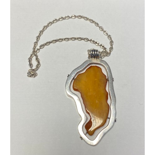 36 - A large modern amber pendant, with silver frame mount and on silver chain -