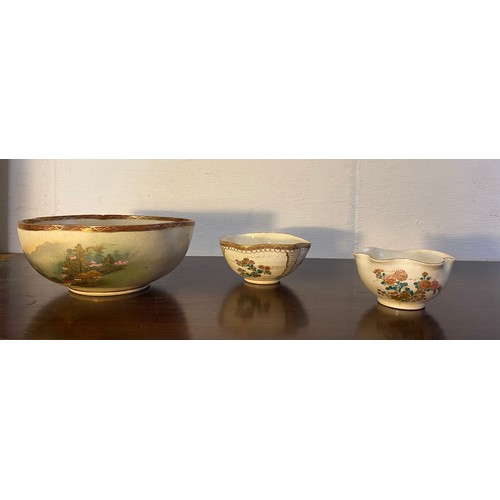 179 - A group of three Japanese Satsuma bowls, the largest decorated with a landscape scene to the centre ... 