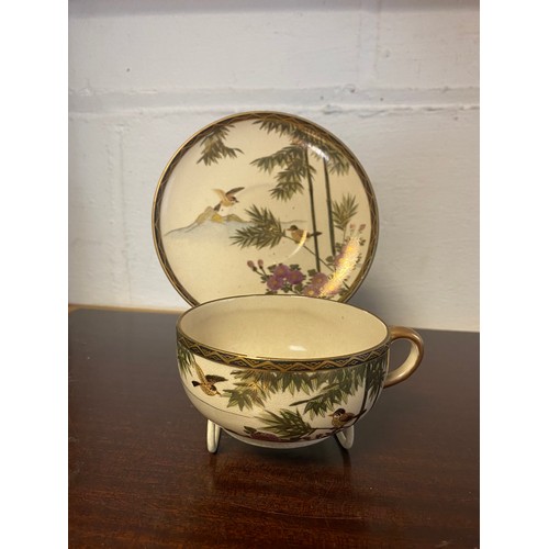 180 - A Japanese Satsuma cup and saucer, decorated with birds on flowering branches -