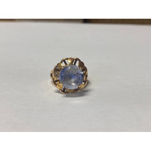 18 - A yellow metal ring, set with a large circular blue sapphire in circular frame and pierced shoulders... 