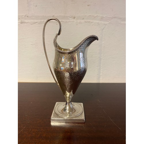 42 - A silver helmet shaped cream jug, marks rubbed, with swagged decoration -