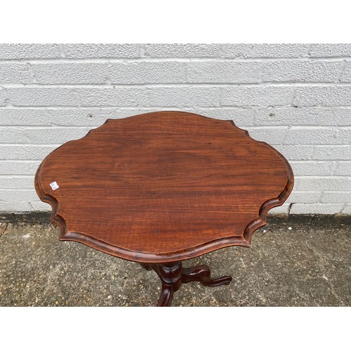 297 - A teak occasional table, with shaped top on central column and three legs -