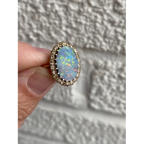 21 - A black opal and diamond cluster ring, the large black opal claw set in a border of single cut diamo... 