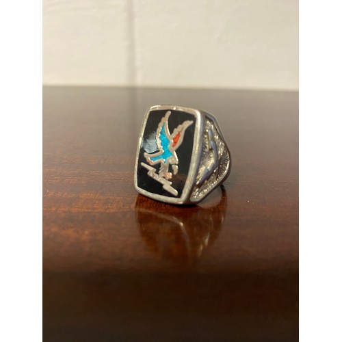 13 - A Native American ring, the panel inset with a crushed turquoise and coral set eagle -