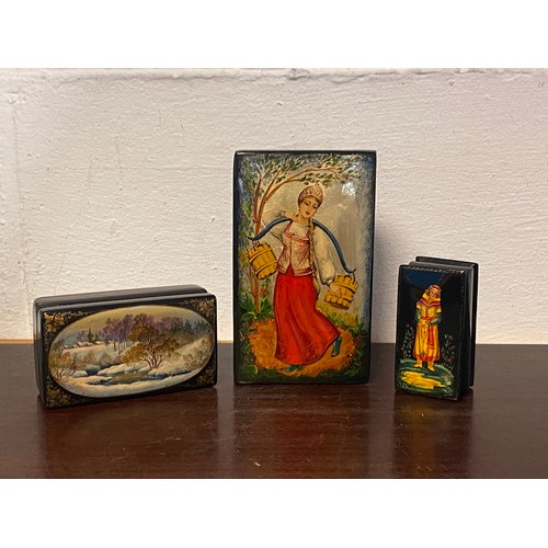 82 - Three lacquered Russian boxes, one decorated with a landscape scene, the other two with figural deco... 