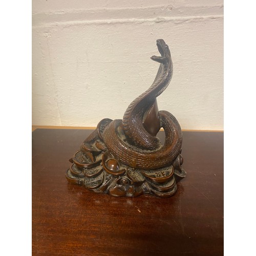 94 - A hardwood Chinese carving, depicting a rearing snake on a pile of coins -