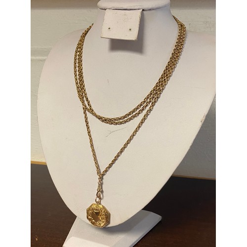 63 - A 9ct gold faceted belcher link long chain, with a dog clip suspending a 9ct gold octagonal locket -