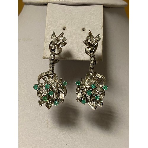 46 - A pair of diamond and emerald ear pendants, the stylised ribbon surmount suspending a row of diamond... 