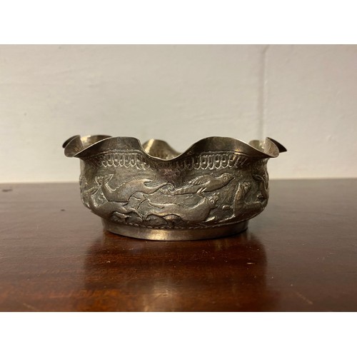 74 - An Indian white metal bowl, with wavy rim above a scene of chasing animals -