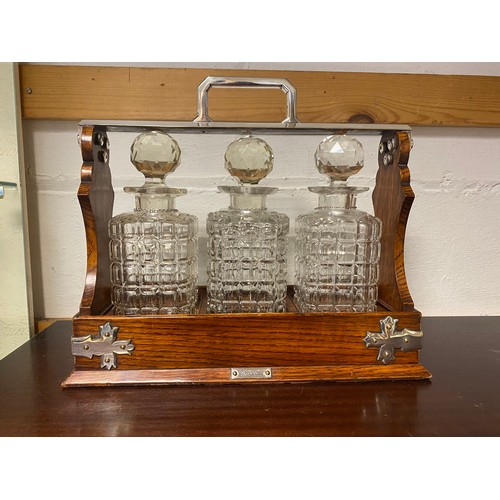 129 - A Mappin & Webb 'The Cabinet' oak and silver plated tantalus, with three cut glass decanters, each w... 