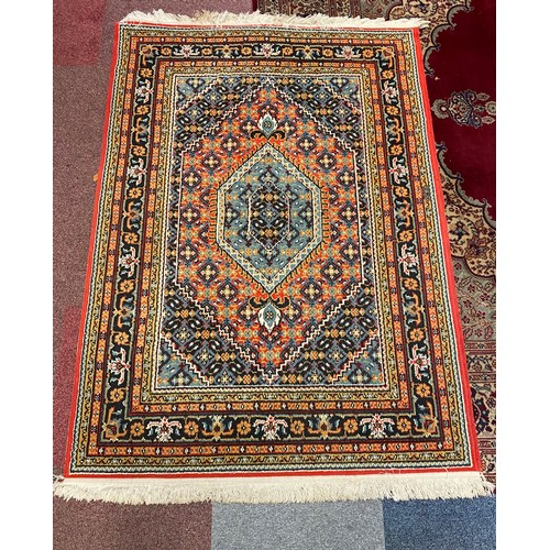 396 - A large rug worked on a red and blue ground and another smaller rug -