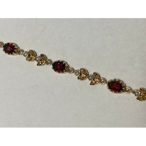 40 - A 9ct gold gem set bracelet, set with oval garnets and pairs of flowerhead links set with seed pearl... 