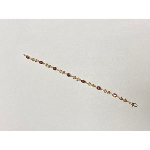 40 - A 9ct gold gem set bracelet, set with oval garnets and pairs of flowerhead links set with seed pearl... 