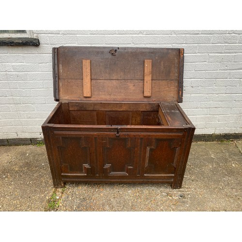 383 - An 18th century oak coffer, with panelled front and short legs, the lift top revealing candle box -