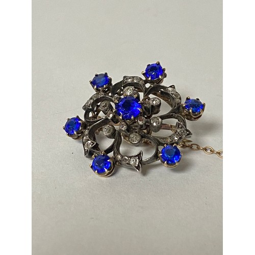 92 - An Edwardian pendant/brooch, of knot design and set with diamonds and blue stones, in precious metal... 