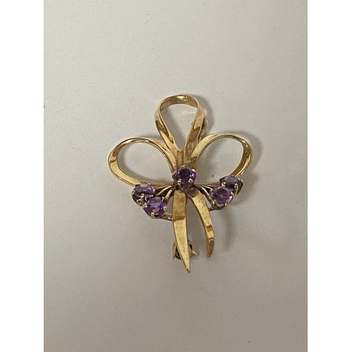 13 - A 9ct gold brooch, set with amethyst in a tied ribbon design -