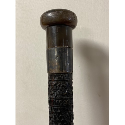 112 - A carved hardwood walking stick, with horn handle and silver collar, over intricately carved taperin... 