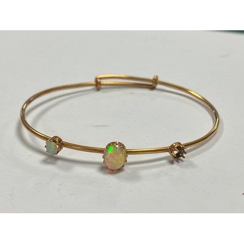 86 - An Edwardian opal set yellow metal bangle (one opal cabochon deficient) -