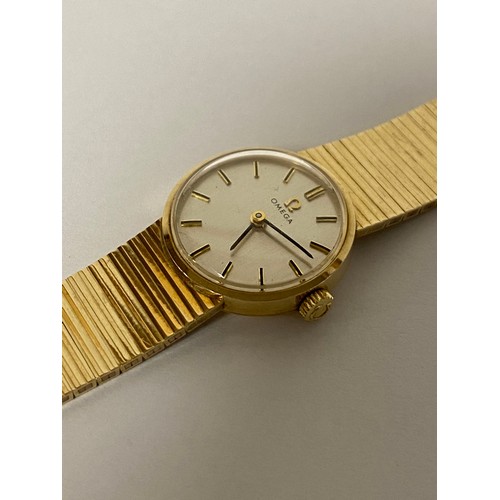 11 - A lady's 9ct gold Omega wristwatch, the signed circular dial to flexible 9ct gold bracelet strap -