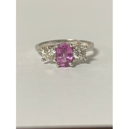 19 - A pink sapphire and diamond three stone ring, set with an oval pink sapphire, flanked by brilliant c... 