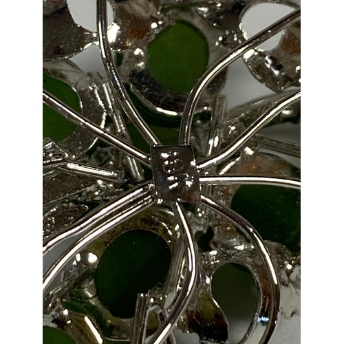 29 - A white metal brooch, set with green stones in a foliate design -